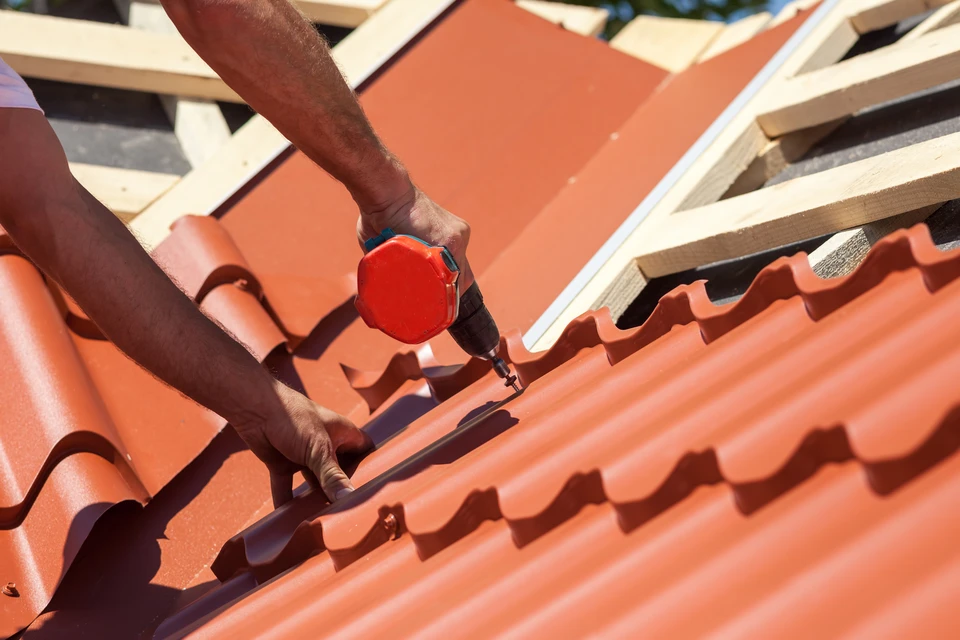 Ouvrier installant des tuiles en terre cuite rouge sur une toiture en construction