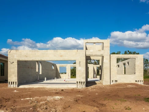 Un maçon qualifié vérifie le niveau de briques fraîchement posées sur un chantier de construction à la lumière du soleil de l'après-midi