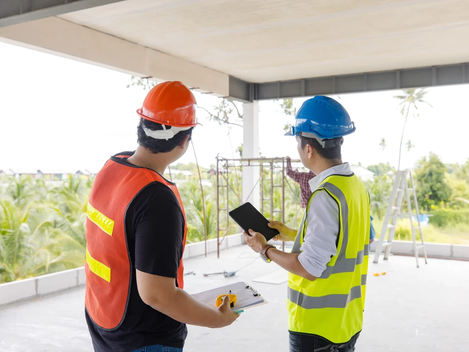 Travailleurs de la construction homme asiatique contremaître portant des vêtements de sécurité travailleur avec des plans et tablette discuter, abonnement travail d'équipe sur le chantier, positivité, collaboration un projet réussi en cours