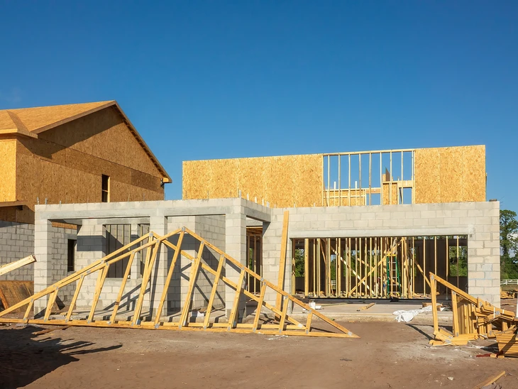Chantier de construction r&eacute;sidentielle en cours, structure b&eacute;ton pr&eacute;fabriqu&eacute; partiellement assembl&eacute;e sous ciel bleu nuageux
