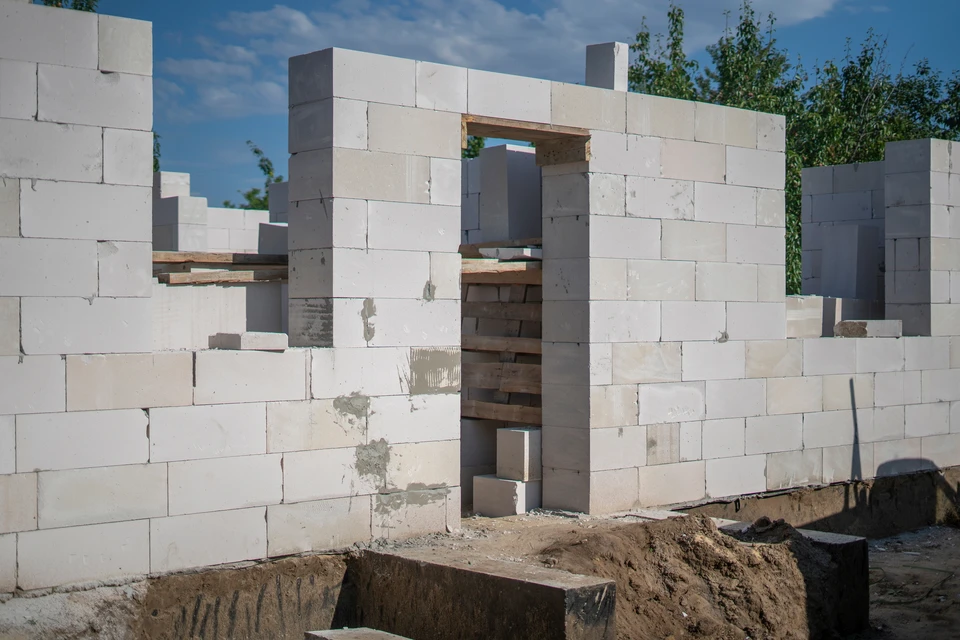 Chantier de construction résidentielle en phase de fondation avec ouvriers posant des blocs de béton