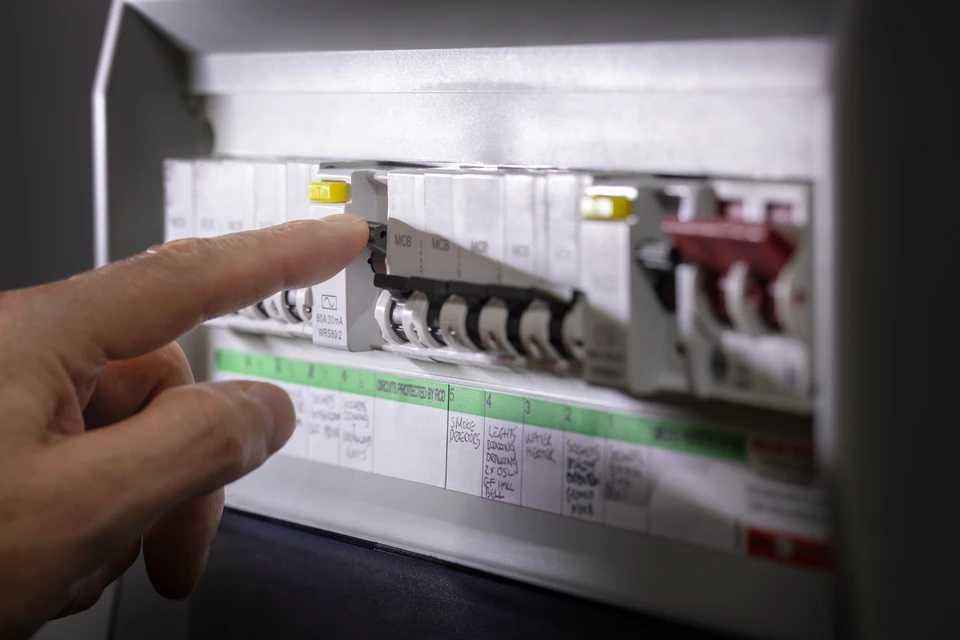 Électricien professionnel en combinaison et gants de protection bleus travaillant sur installation électrique murale