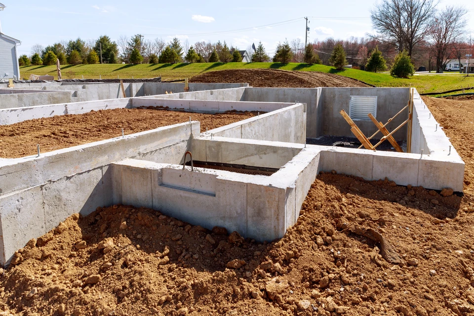 Un maçon qualifié vérifie le niveau de briques fraîchement posées sur un chantier de construction à la lumière du soleil de l'après-midi